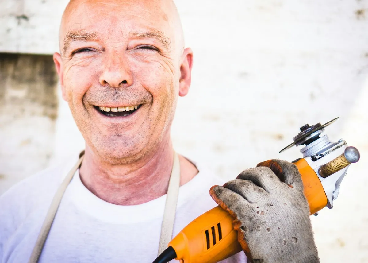 Artisan souriant avec sa meuleuse