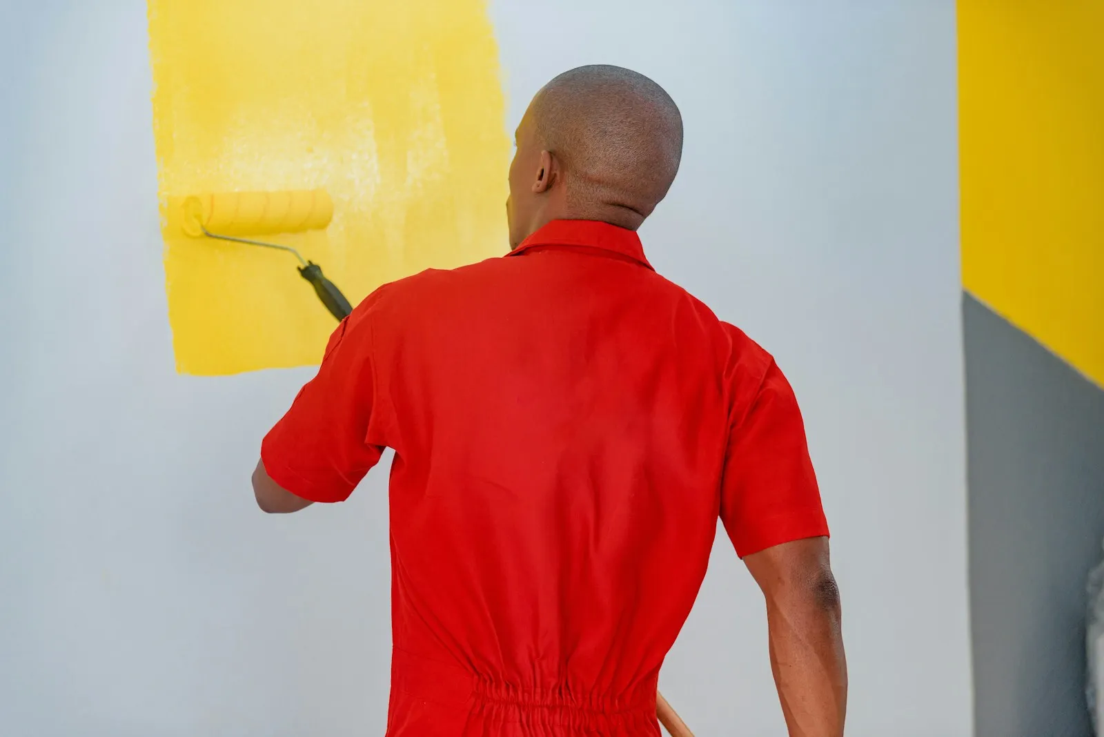Peintre appliquant une peinture jaune au rouleau