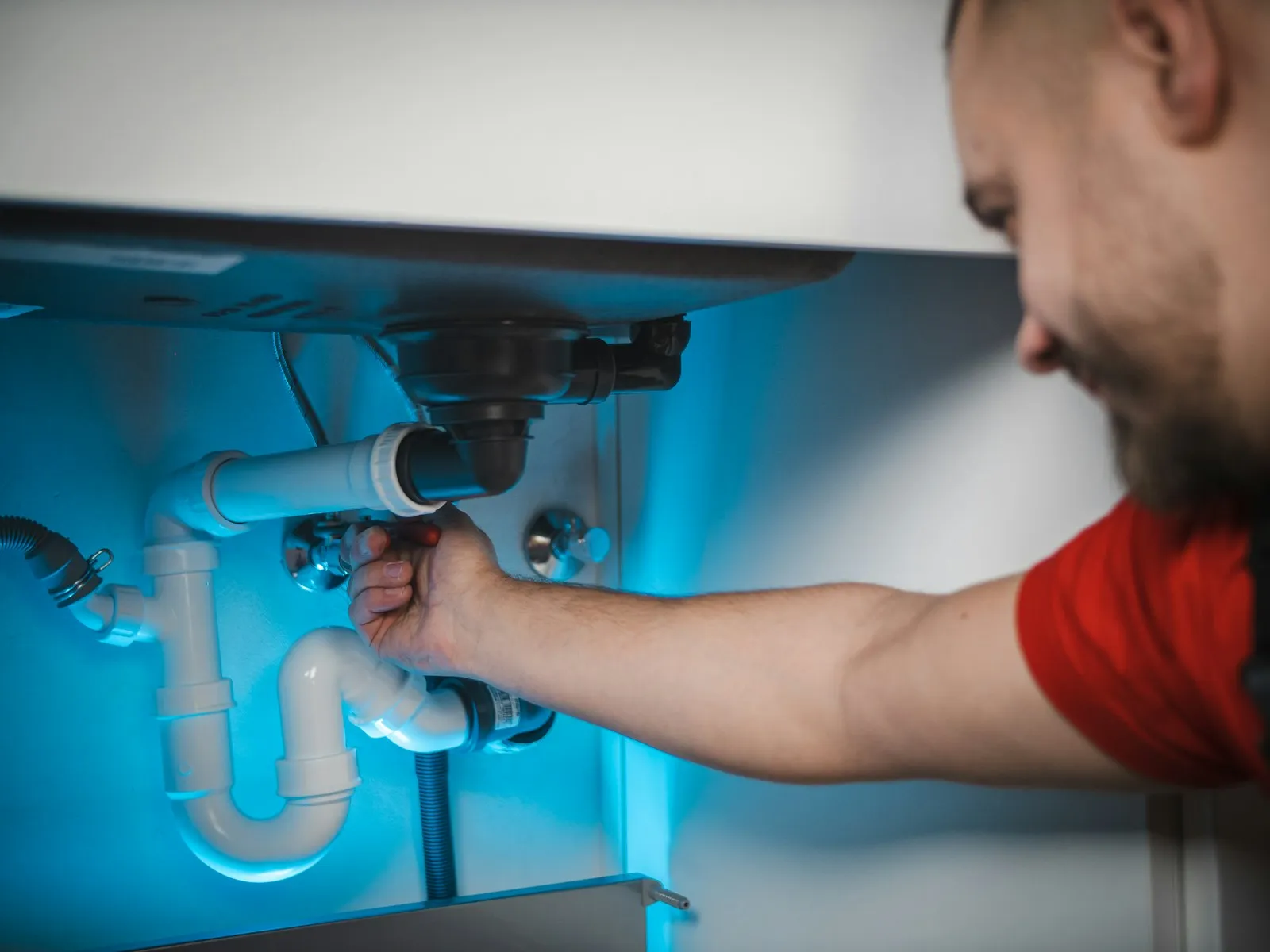 Plombier réparant une évacuation sous un lavabo